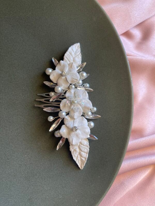 White floral headpiece with white leaves .